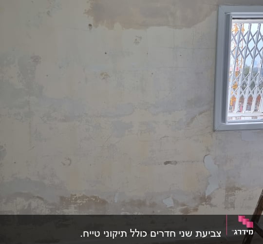 קיר עם טיח מתקלף וכלי צביעה על הרצפה